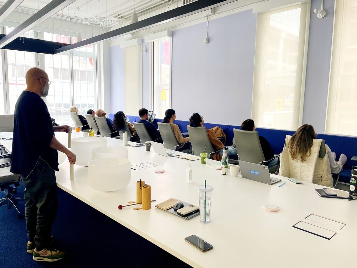 A boardroom sound bath, the team in their chairs around the table