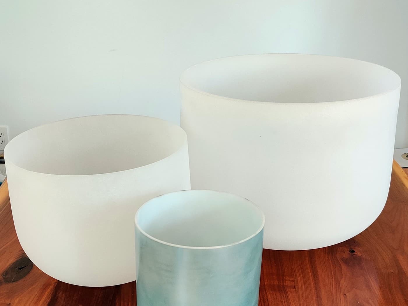 Three crystal bowls on a walnut table, the smallest one pale blue