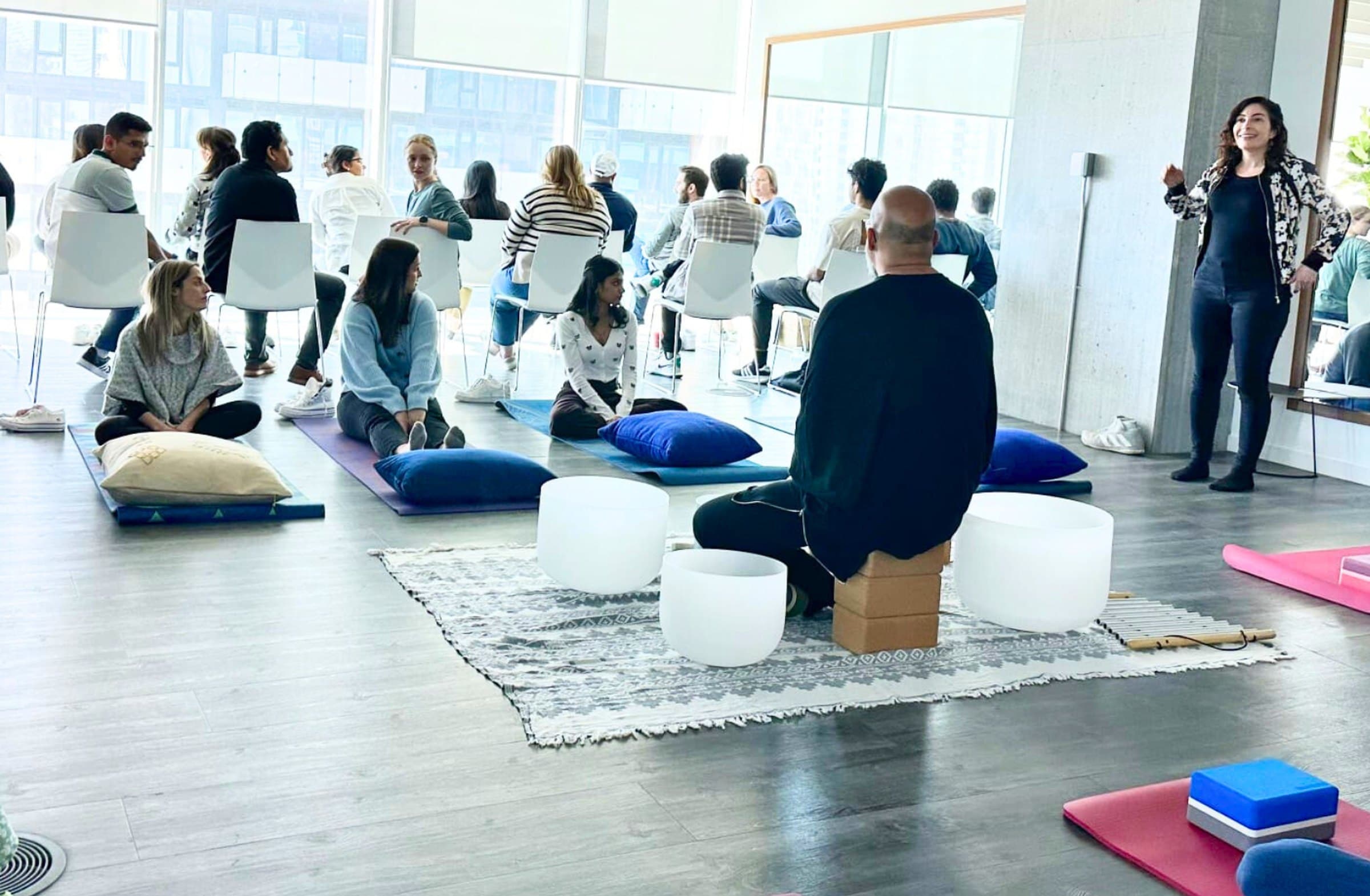 A team seated on chairs and mats during a sound bath in their office