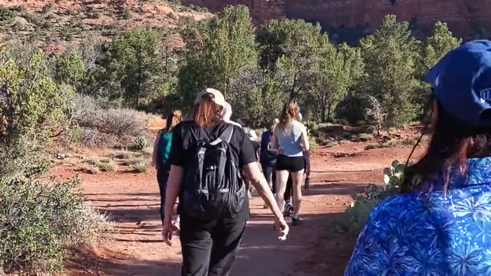 A small group walking together along a red dirt trail in Sedona during a retreat