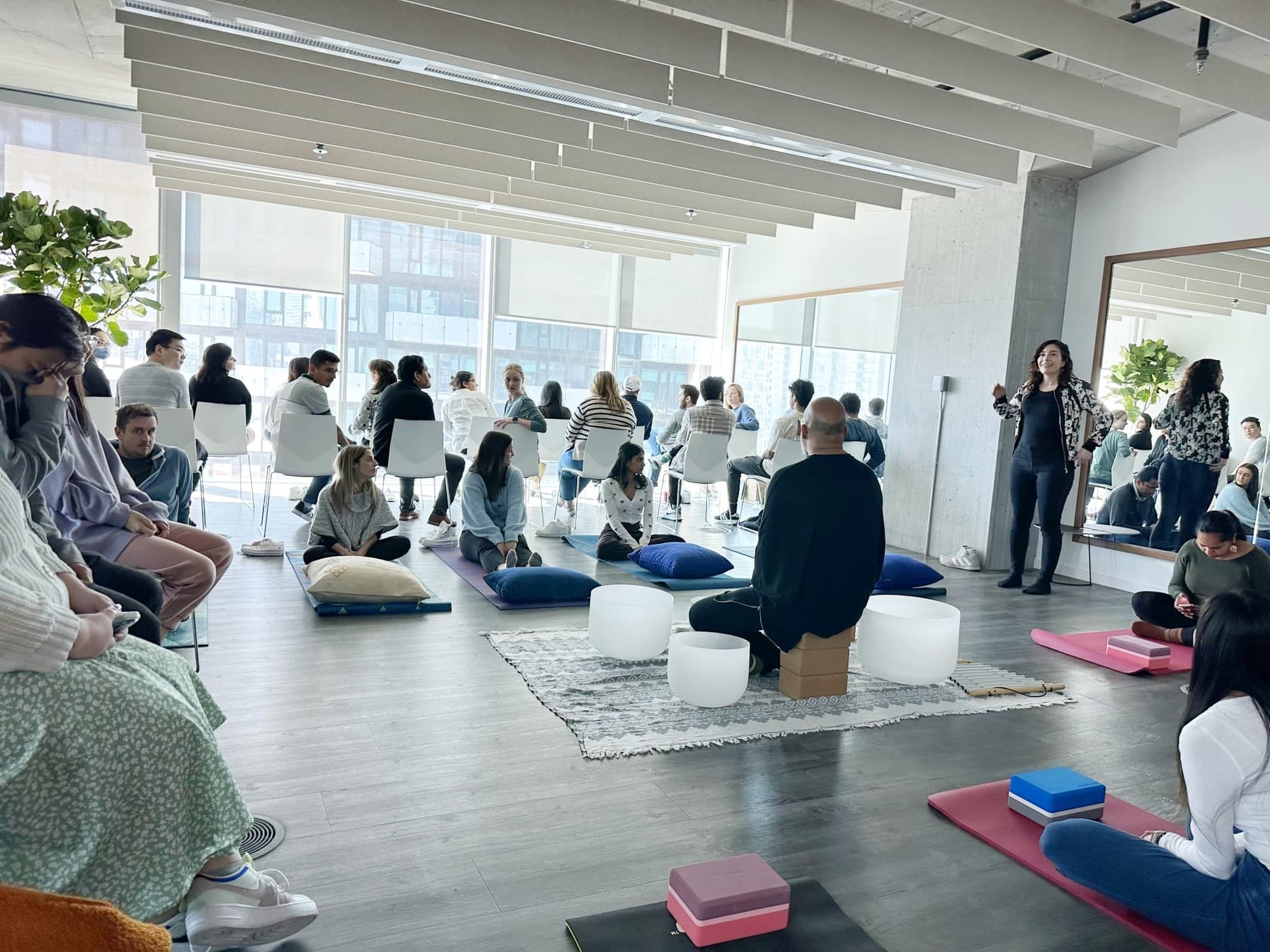 A wide view of an office sound bath, rows of chairs behind people lying on mats