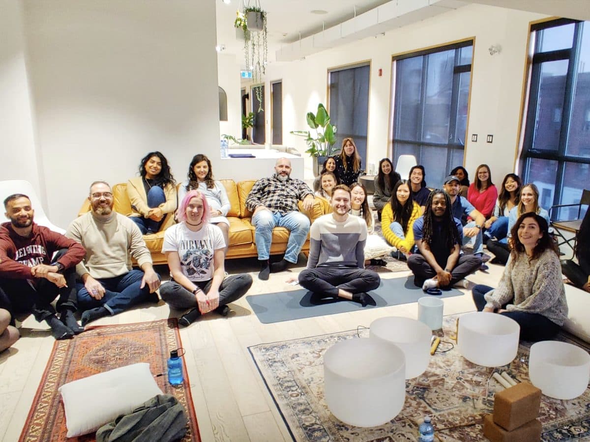 A team gathered on sofas and cushions around the crystal bowls, smiling after a session